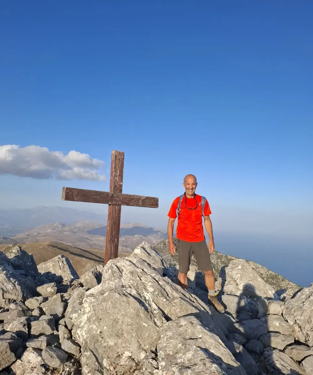 Πεζοπόρος στέκεται σε ορεινή ράχη κάτω από σύννεφα.